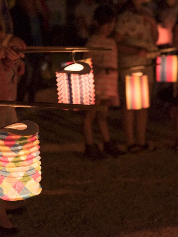 Des enfants et des adultes portent des lanternes en papier par une chaude soirée d’été