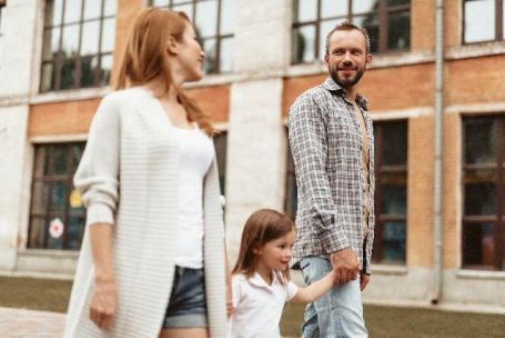 parents se promènent dans la rue et donnent la main à leur fille